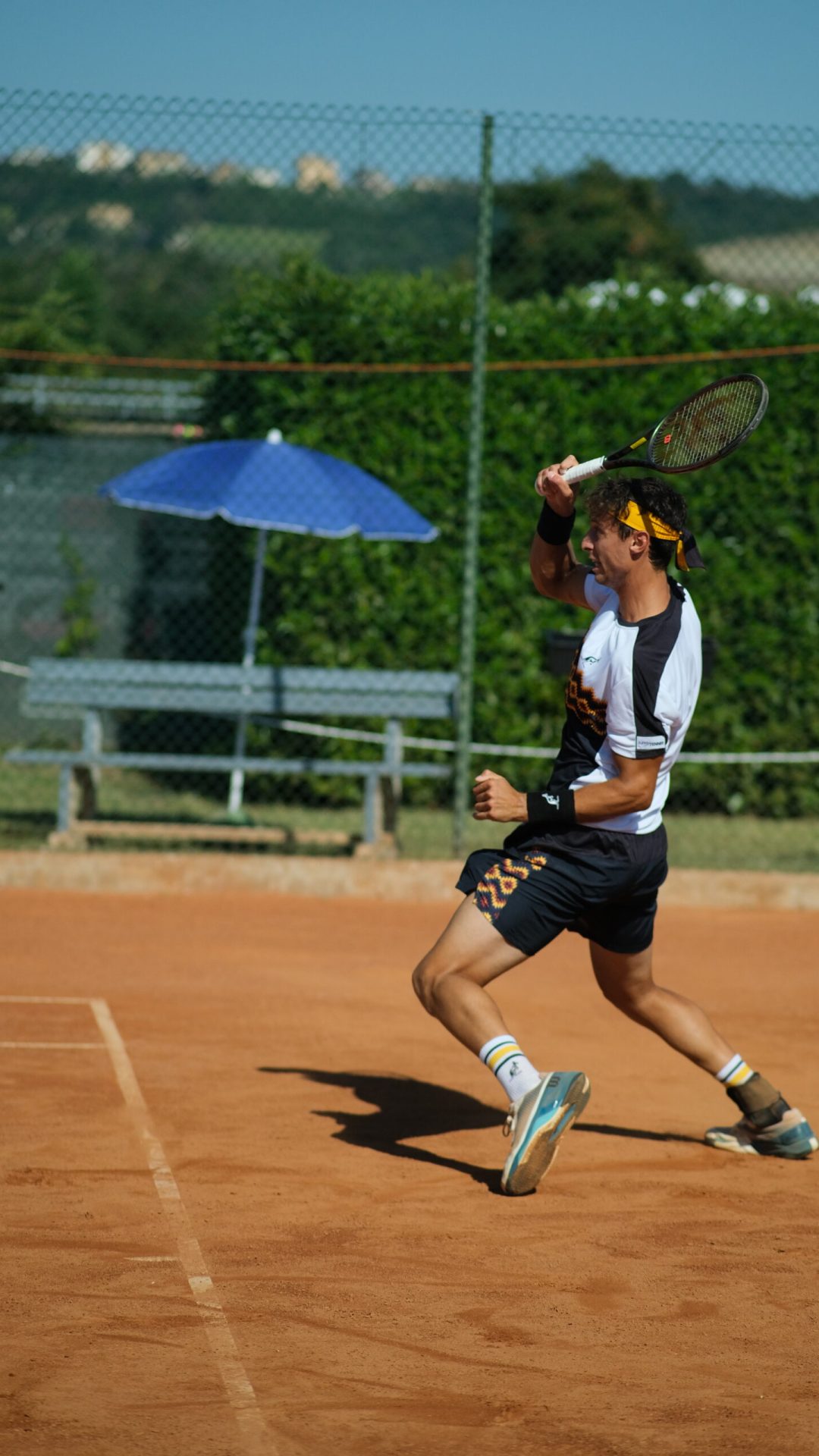 Un videomaker cattura un uomo che fa oscillare con grazia una racchetta da tennis su un campo da tennis.